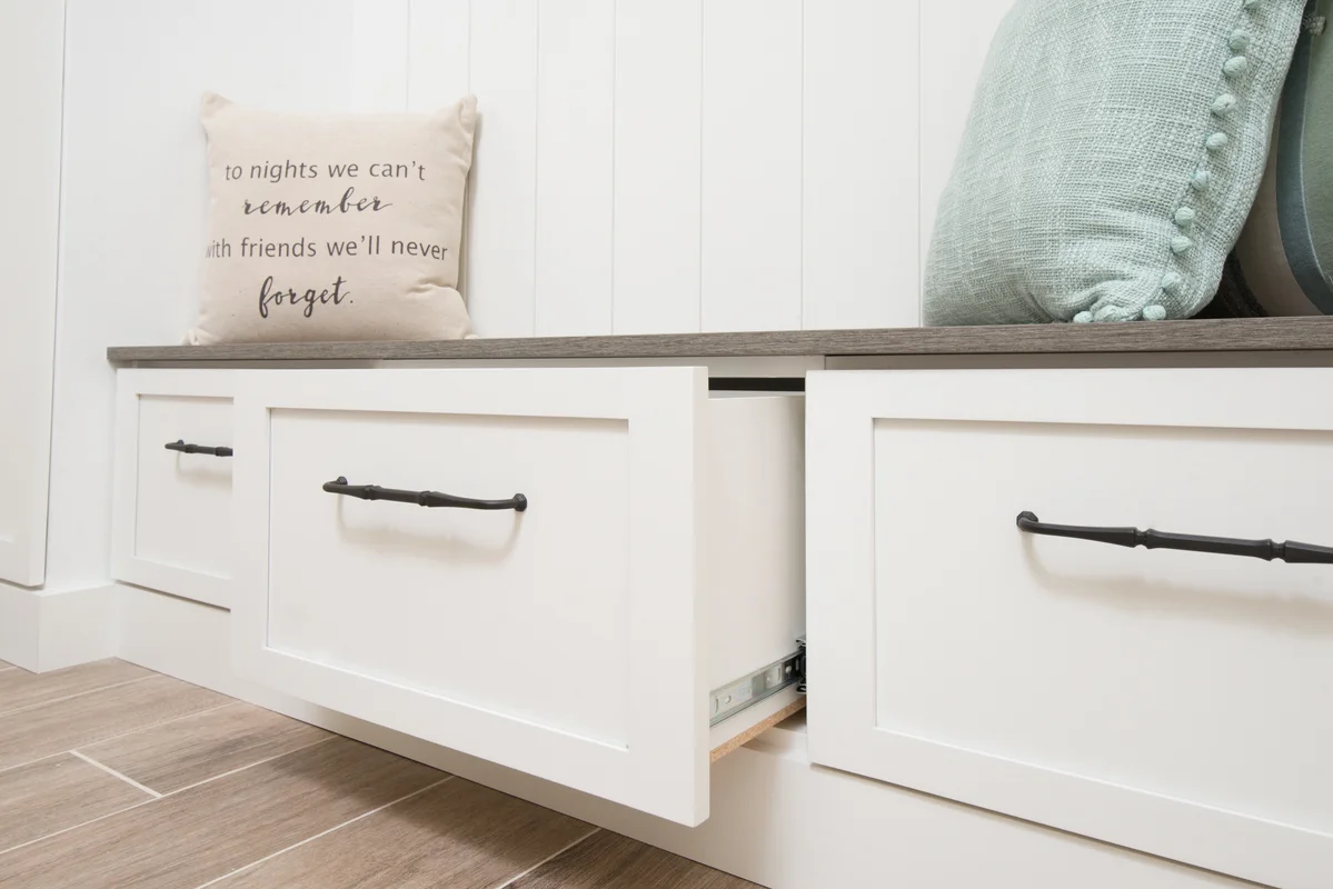 White mudroom bench with storage drawers and decorative pillows