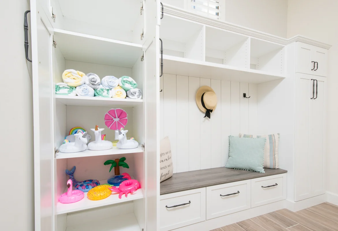 White mudroom with pool toy storage and built-in bench