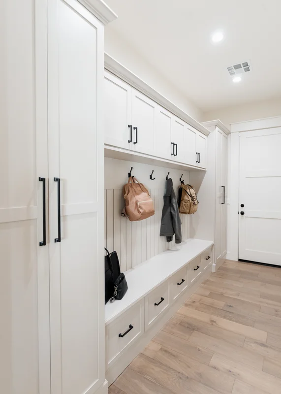 White mudroom hallway with coat hooks and drawer storage