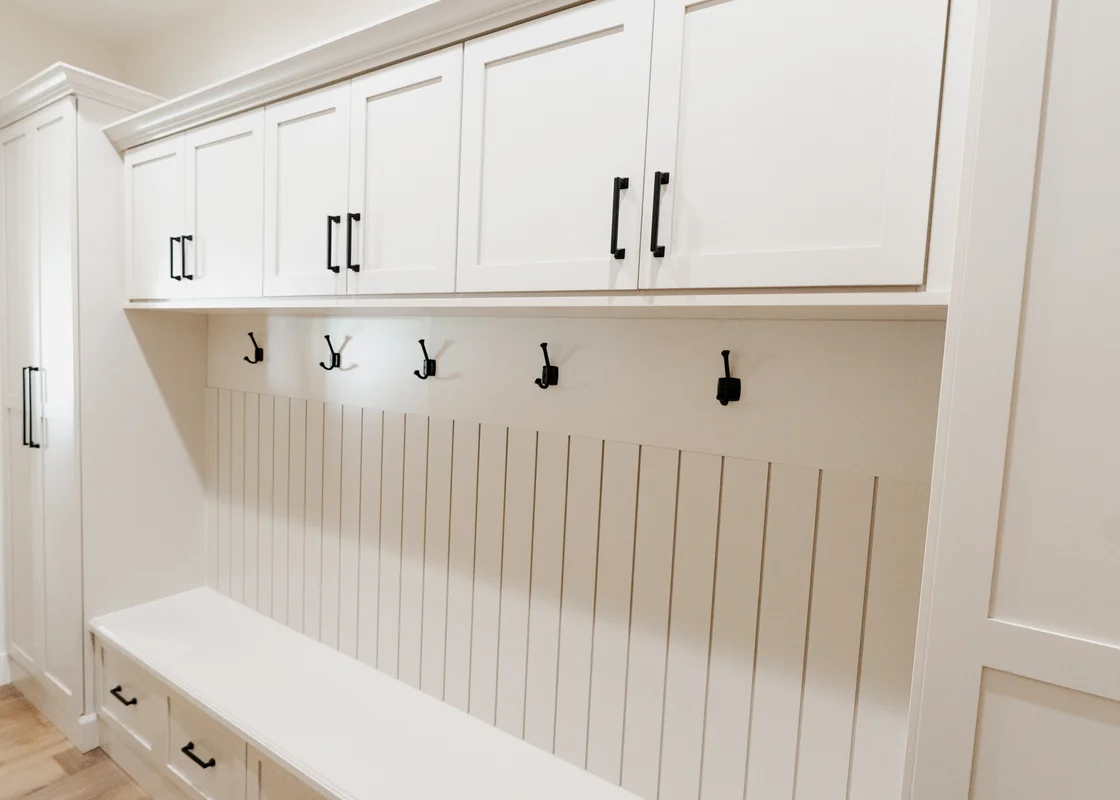 White shaker mudroom with hooks and upper cabinets