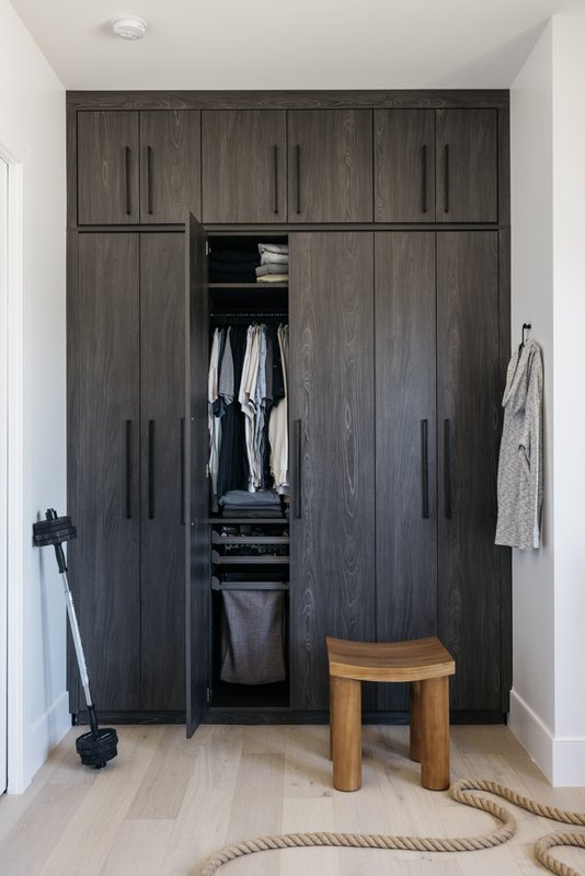 Custom dark wood reach-in closet with built-in hamper and shelving