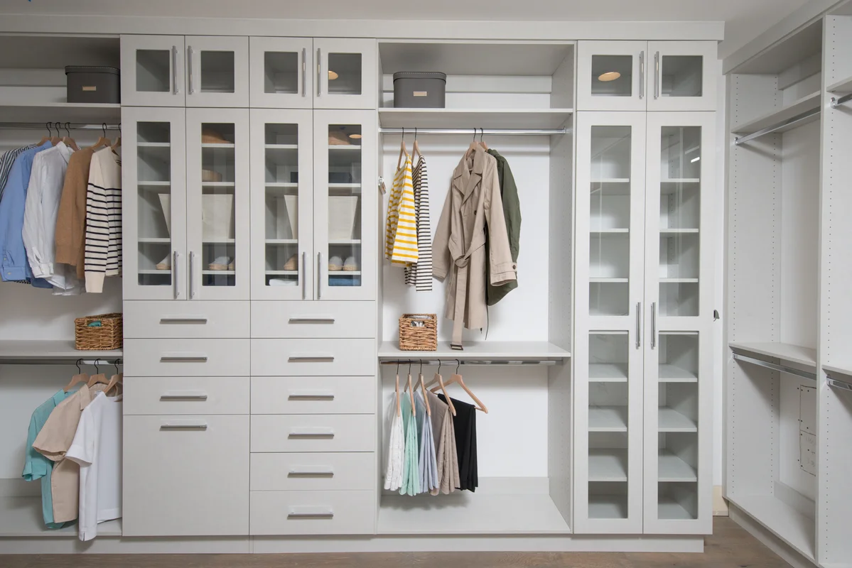 White custom closet with glass doors and organized storage