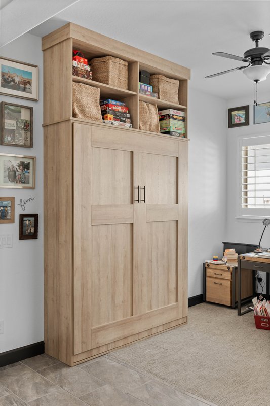 Oak finish Murphy bed closed with decorative storage above